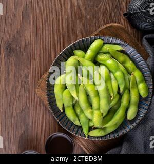 Frisch gekochte gekochte Edamame in einem Teller auf Holztablett und Tischhintergrund, Protein-Food-Konzept. Stockfoto