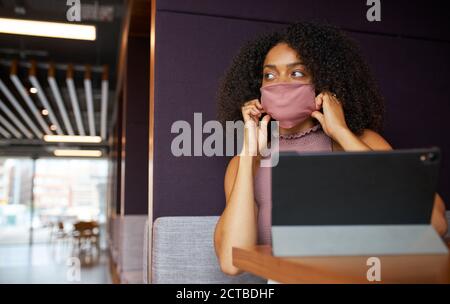 Geschäftsfrau Trägt Maske Arbeitet In Sozial Distanzierten Kabine Im Büro Während Der Gesundheitsinpandemie Stockfoto