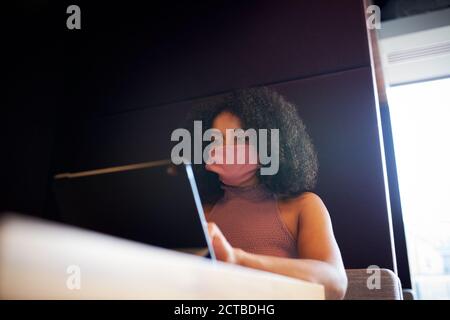 Geschäftsfrau Trägt Maske Arbeitet In Sozial Distanzierten Kabine Im Büro Während Der Gesundheitsinpandemie Stockfoto