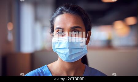 Weibliche Doktor In Gesichtsmaske Trägt Scrubs Unter Druck In Vielbeschäftigter Krankenhaus Während Gesundheit Pandemie Stockfoto