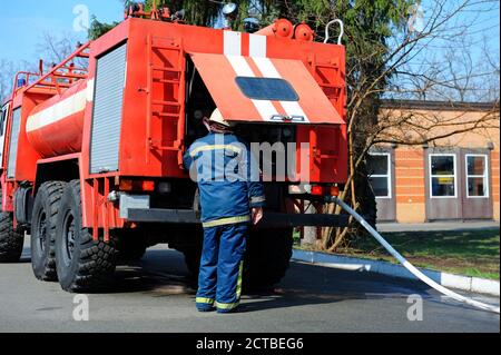 Feuerwehrmann, Wasserpumpe eines Feuerwehrfahrzeugs, Schlauch angeschlossen Stockfoto