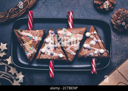 Weihnachtsbaum Brownies mit Zuckerrohr und Glasur, dunkler Hintergrund. Weihnachtsessen Konzept. Stockfoto
