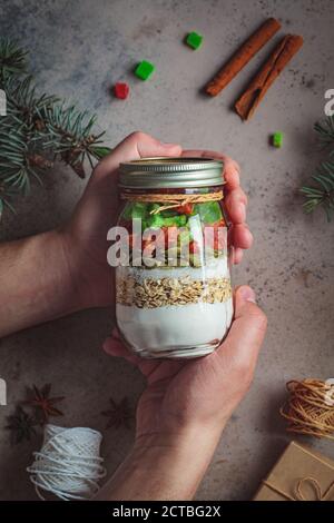 Weihnachts-Plätzchen Mixglas. Trockene Zutaten zum Kochen von Weihnachtskeksen in einem Glas, dunkler Hintergrund. Weihnachtsessen Konzept. Stockfoto