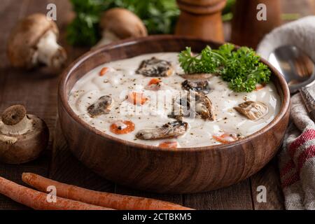 Schüssel mit Sahne Pilzsuppe und Zutaten auf rustikal Holztisch Stockfoto