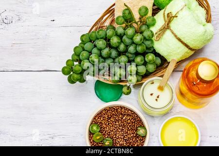 Natürliche Spa-Accessoires und grüne Trauben. Frische Zutaten für eine gesunde und komfortable Selbstpflege. Weiße Holzbretter Hintergrund, Draufsicht Stockfoto