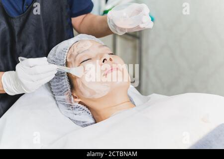 Frau mit Gesichtsbehandlung im Spa mit Kosmetikerin Anwendung Maske auf Dame Gesicht. Stockfoto