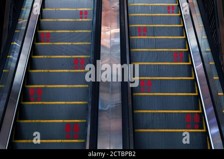 Aufkleber Fußdruck für halten soziale Distanzierung Symbol auf Rolltreppe Des neuen normalen Verhaltens für Sicherheit zuerst in covid-19 Coronavirus Pandemie im Büro Stockfoto