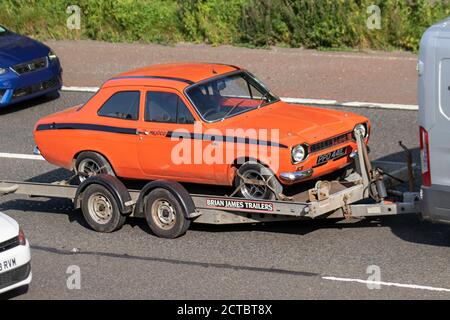 1972 70s orange rot Ford Escort Mexiko auf Anhänger; Fahrzeug Verkehr Moving Vehicles, Autos fahren Fahrzeug auf britischen Straßen, 70s Motoren, Fahren auf der Autobahn M6 Autobahnnetz. Stockfoto