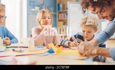 Grundschule Kunst Handwerk Klasse: Begeisterter Lehrer, verschiedene Gruppe von intelligenten Kindern Spaß haben zusammen auf Handwerk Projekt, mit bunten Stockfoto