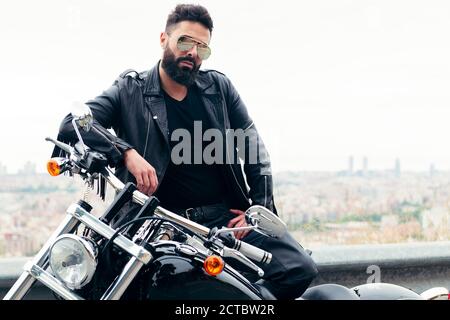 Mann in Leder gekleidet und trägt Sonnenbrillen Posen neben seinem Motorrad, Konzept der Freiheit und Biker-Lifestyle, Copy Platz für Text Stockfoto