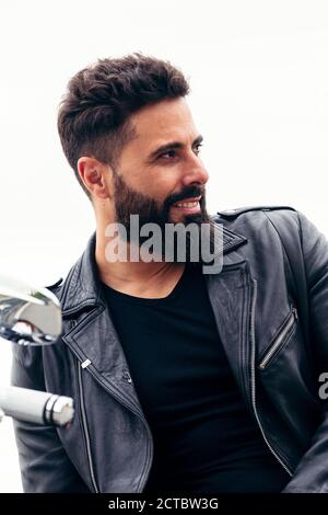 Porträt eines hübschen bärtigen Mannes in Leder gekleidet lehnt auf seinem Motorrad, Konzept der Freiheit und Biker-Lifestyle, Kopierer Platz für Text Stockfoto