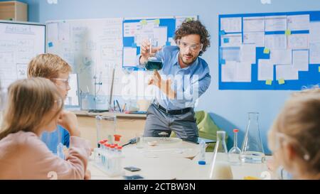 Grundschule Chemie Klassenzimmer: Begeisterter Lehrer unterrichtet Gruppe von Kindern, zeigt Wissenschaft Experiment durch Mischen von Chemikalien im Becher Stockfoto