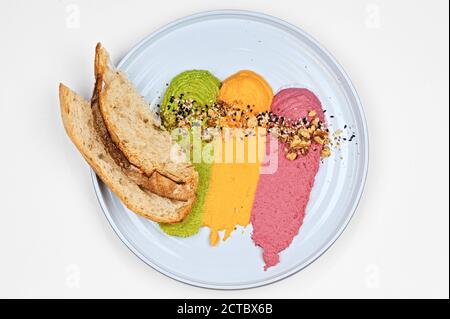Bunte vegane Gericht Hummus aus Hülsenfrüchten mit Croutons, Sesam und Walnüsse Dekoration auf Teller Draufsicht Stockfoto