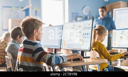 Grundschule Informatik Klassenzimmer: Smart Little Schoolboy Arbeit an Personal Computers, lernen Programmiersprache für Software-Codierung Stockfoto