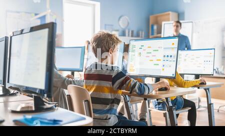 Grundschule Informatik Klassenzimmer: Intelligente kleine Schüler arbeiten an Personal Computers, lernen Programmiersprache für Software-Codierung Stockfoto