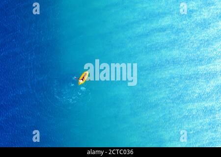 Gelbes Packraft Gummiboot und türkisfarbene Wasserwellen von oben. Aktive Reise Sommerferien Seestück Hintergrund von Drohne Stockfoto