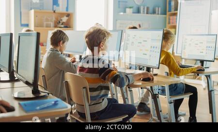 Grundschule Informatik Klassenzimmer: Intelligente kleine Schüler arbeiten an Personal Computers, lernen Programmiersprache für Software-Codierung Stockfoto