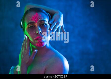 Portrait der schönen jungen Frau mit fluoreszierenden Make-up auf Gesicht und Haut in ultraviolettem Licht. Kunst und Sinnlichkeit Konzept. Stockfoto