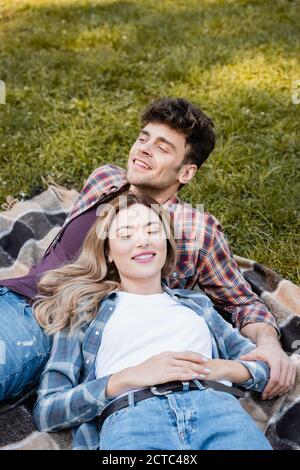 Mann und Frau in karierten Hemden, die auf einer Decke liegen Stockfoto