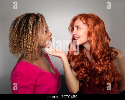 Horizontales Profilbild einer weißen Frau, die das Kinn hält Ihrer schwarzen Freundin Stockfoto