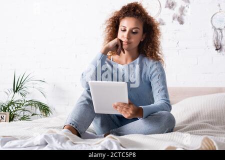 Selektiver Fokus der jungen Frau mit digitalen Tablet während des Sitzens Auf dem Bett Stockfoto