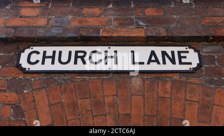 Altes englisches Straßenschild mit der Aufschrift Church Lane auf der Plakette Zum Mauerwerk Stockfoto