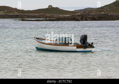 Ein Hummertopf in einem kleinen Holzboot vor Anker von Green Porth, Tresco, Isles of Scilly Stockfoto