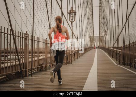 Praktizierende Frau Joggen auf der Brooklyn Bridge Stockfoto