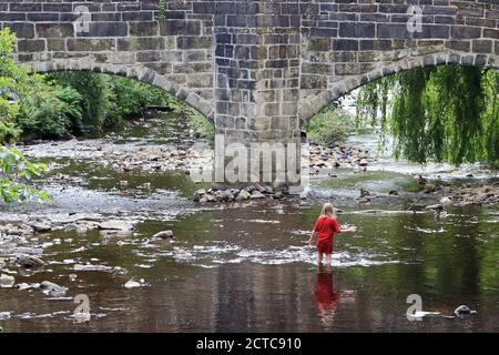 Junges Mädchen spielt in Hebden Wasser Stockfoto