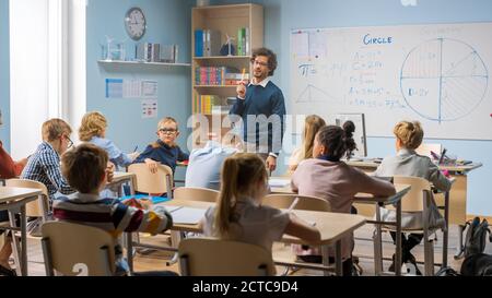 Fürsorglicher Lehrer erklärt Lektion zu einem Klassenzimmer voller heller vielfältiger Kinder. In der Grundschule mit Gruppe von intelligenten multiethnischen Kinder lernen Stockfoto