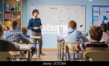 Fürsorglicher Lehrer erklärt Lektion zu einem Klassenzimmer voller heller vielfältiger Kinder. In der Grundschule mit Gruppe von Smart Multiethnic Learning Science Stockfoto