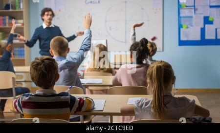 Fürsorglicher Lehrer erklärt Lektion zu einem Klassenzimmer voller verschiedener Kinder. In der Schule mit Gruppe von Smart multiethnic Kids Learning Science, ganz Stockfoto