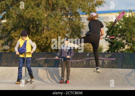 Moskau, Russland - 11. September 2020: Teenager führt einen Trick in der Stadt Skatepark. Roller schieben. Er springt über ein Hindernis. Extremsport ist Stockfoto