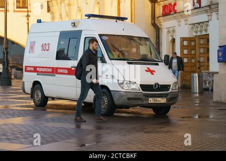 Moskau, Russland - 10. September 2020: Moskau Stadtbild bei Herbstuntergang nach dem Regen. Konzept des Großstadtlebens. Junger Mann beim Gehen. Notauto Stockfoto