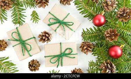Weihnachtspostkarte mit Bastelschachteln, Tannenzweigen, Zapfen und roten weihnachtskugeln auf weißem Hintergrund. Stockfoto