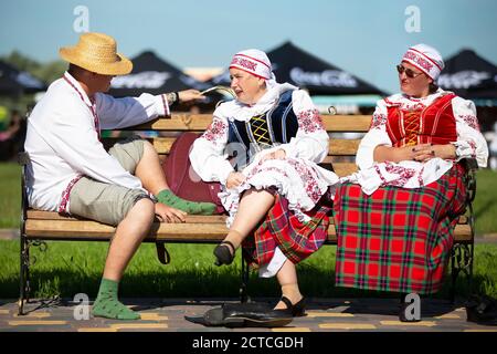 08 29 2020 Weißrussland, Ljaskowitschi. Feier in der Stadt. Auf der Bank sitzen Menschen in nationalslawischer Kleidung. Weißrussen oder Ukran Mann und Stockfoto