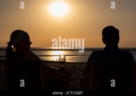 Silhouette eines jungen Paares auf der Promenade beim Sonnenuntergang auf der Insel Borkum, Friesland, Niedersachsen, Deutschland, Europa. Stockfoto