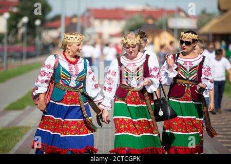 08 29 2020 Weißrussland, Ljaskowitschi. Ein Urlaub in der Stadt. Frauen in nationalslawischer Kleidung laufen die Straße entlang. Ukrainisch oder Weißrussisch. Stockfoto