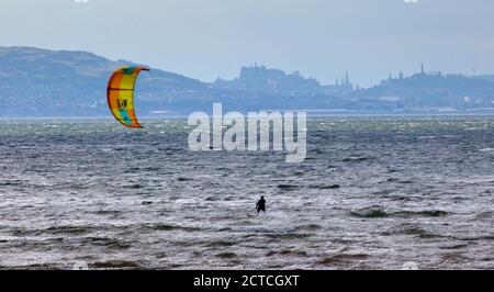 Longniddry, East Lothian, Schottland, Großbritannien. 22. September 2020. Windig und dunstig bei Longniddry Bents, gute Bedingungen für Kite Surfers, mit einem dunstig Edinburgh Castle und Calton Hill im Hintergrund, Temperatur von 16 Grad. Stockfoto