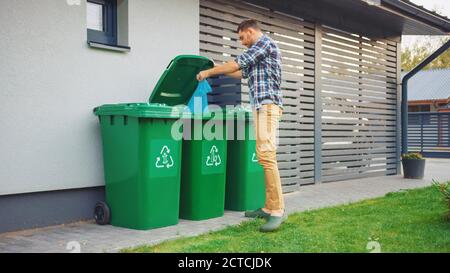 Kaukasischer Mann ist wegwerfen Plastiktüten mit sortierten Müll. Konzept der Abfallsortierung für Lebensmittel, Papier und Flaschen. Umgebung wird aus dem Papierkorb gespeichert. Stockfoto