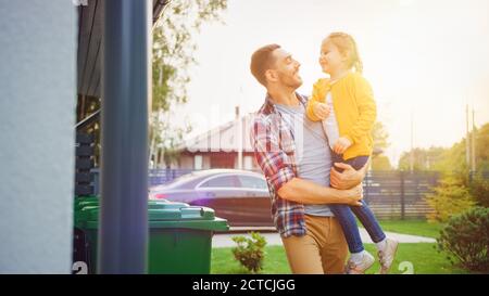 Glücklicher Vater hält ein junges Mädchen. Sie warfen Müll in richtige Mülltonnen, weil diese Familie Abfall sortiert und der Umwelt hilft Stockfoto