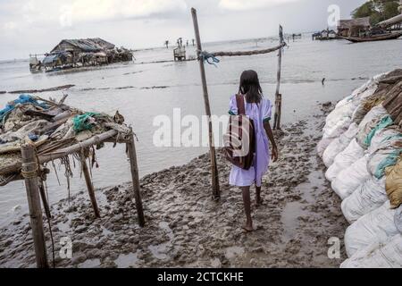 Westbengalen, Indien. August 2017. Ein junges Mädchen von Mousuni Island geht barfuß mit ihrem Rucksack auf dem Weg zur Schule entlang des schlammigen Ufers. Die Nutzung von Booten auf den Gewässern ist die Hauptverkehrsform in den Sundarbans. Kredit: Supratim Bhattacharjee/ZUMA Wire/Alamy Live Nachrichten Stockfoto