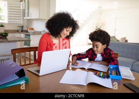 Mutter hilft Sohn mit Hausaufgaben zu Hause Stockfoto