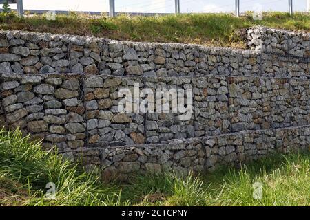 Ein Fragment einer Stützmauer aus Gabionen. Verstärkung des steilen Gefälles. Stockfoto