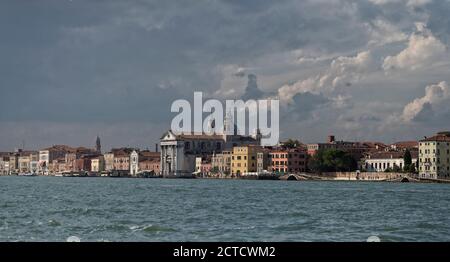 Venedigs Wasserfront mit einer Basilika und anderen lokalen Volkskundbauten. Schuss aus der Lagune auf einem Boot. Stockfoto