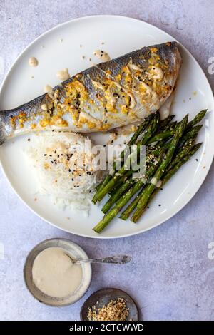 Gebackener Seebarsch mit Zitronengras, Ingwer, Tahini-Sauce und Sesamsamen Stockfoto