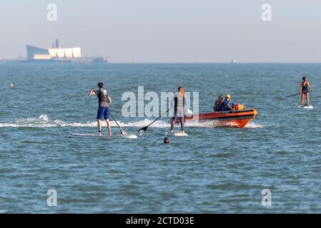 Sicherheitsbootkontrolle an Paddelboardern vor Southend on Sea, Essex, Großbritannien. Wassersport in der Themse Mündung. Wassersport Aktivität im Meer mit Motor Schlauchboot Stockfoto