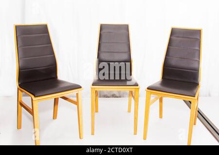 Drei moderne neue Holzstühle mit Ledersitzen in der Werkstatt. Stockfoto