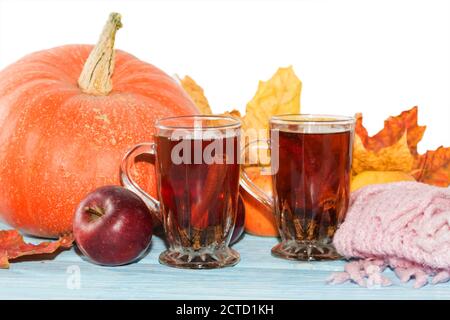 Herbsthintergrund, Kürbis, Äpfel mit gelben Blättern und Tee in Tasse auf Holztisch auf weißem Hintergrund. Stockfoto