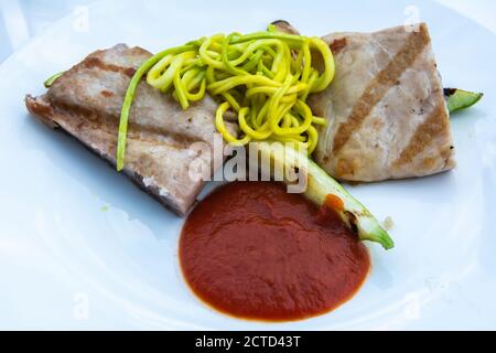 Teller mit zwei Stücken Schweinefleisch, Zucchini Spaghetti und Tomatensauce, in Russland. Stockfoto